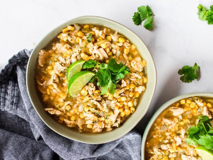 A green bowl of Salsa Verde Chicken Soup filled with chicken and corn.