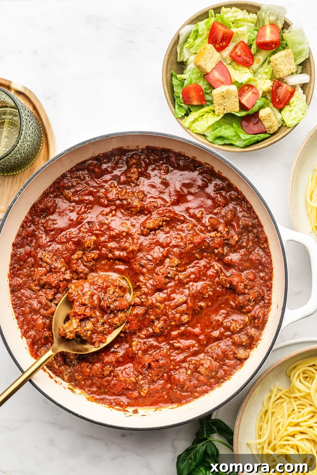 A bowl of freshly cooked spaghetti generously topped with homemade meat sauce and garnished with basil