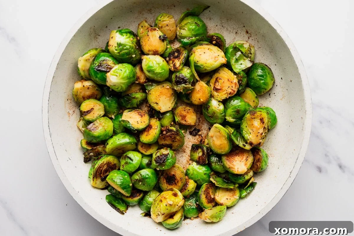 Balsamic Glazed Bacon Brussels Sprouts 4 Ingredients for Balsamic Bacon Brussels Sprouts laid out on a cutting board: fresh brussels sprouts, diced bacon, garlic, and a bottle of balsamic vinegar.