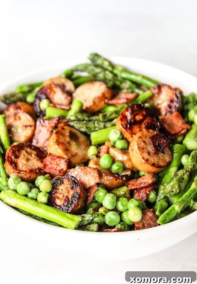 Spring Sausage Quick Fix 2 Close-up of Quick Sausage & Spring Veggies Skillet, featuring browned sausage slices, crispy bacon, bright green asparagus spears, and sweet peas, all in a large skillet.