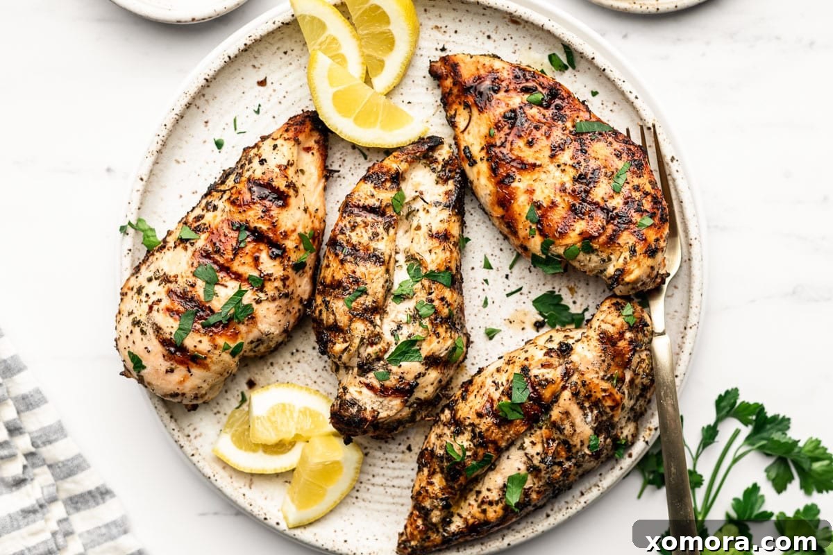 Vibrant Lemon Herb Grilled Chicken 5 Close-up of chicken breasts marinating in a clear glass dish with lemon and herbs.