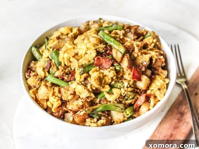 Brunch Bliss Scramble 3 A close-up view of the breakfast scramble in a large cast iron skillet, showcasing the golden-brown potatoes, vibrant green beans, and scrambled eggs, with a sprinkle of fresh herbs.
