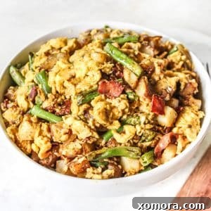 Brunch Bliss Scramble 5 A top-down view of the prepared Weekend Breakfast Scramble in a rustic bowl, garnished with green onions and a side of hot sauce, highlighting its appetizing appearance.