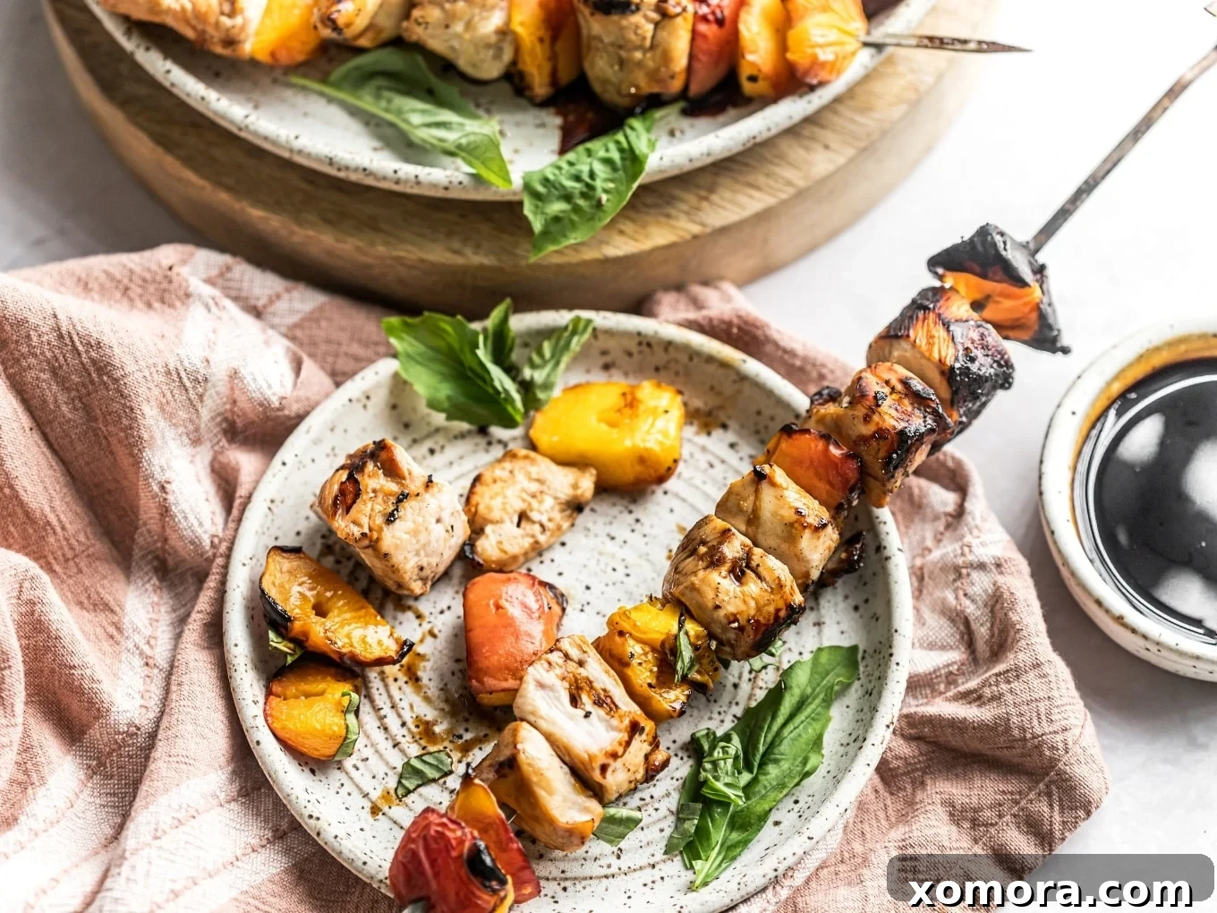 Wholesome Grilling Delights 10 Grilled Balsamic Peach Chicken Kabobs on a plate, garnished with fresh basil.