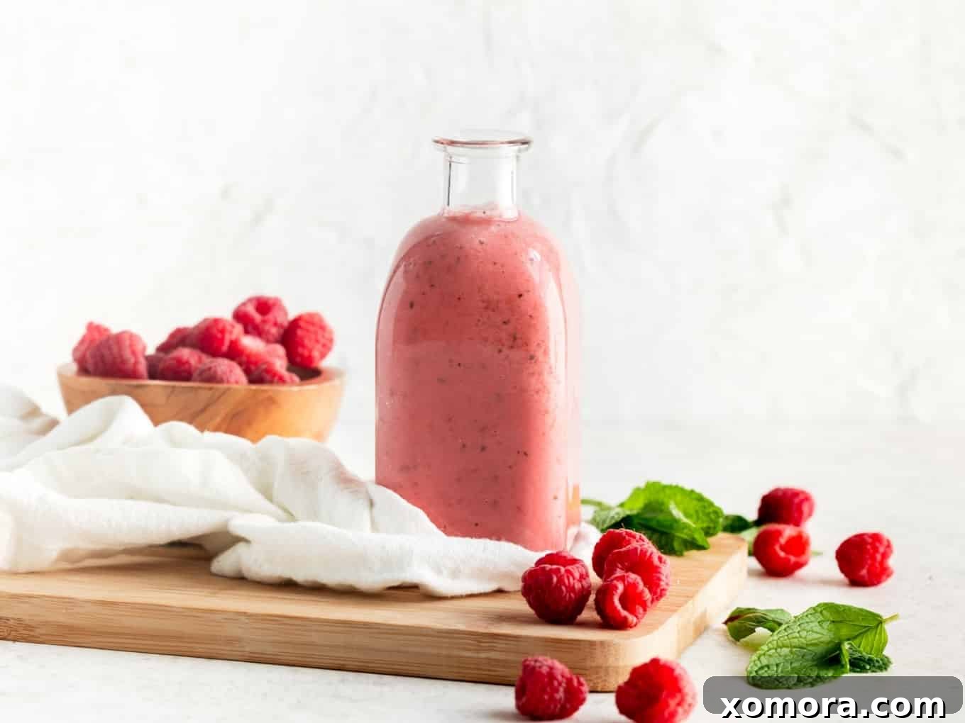 Flavorful & Guilt-Free Salad Dressings 17 Glass bottle of vibrant Raspberry Mint Dressing with fresh mint leaves.