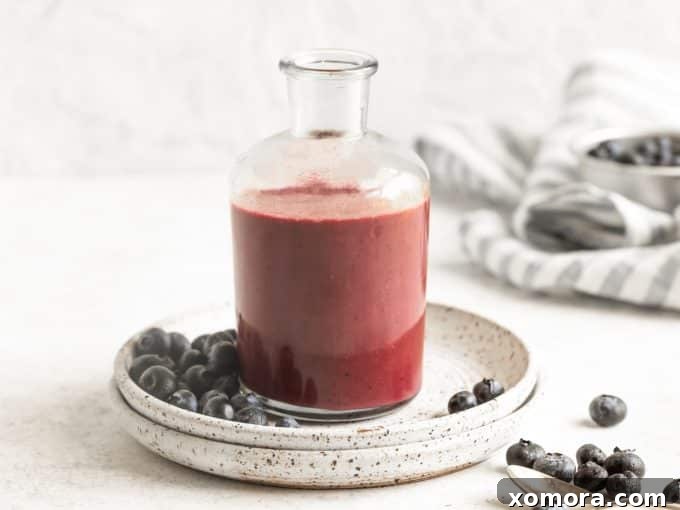 Flavorful & Guilt-Free Salad Dressings 7 A bowl of mixed greens topped with blueberries and a drizzle of vibrant Blueberry Dressing.