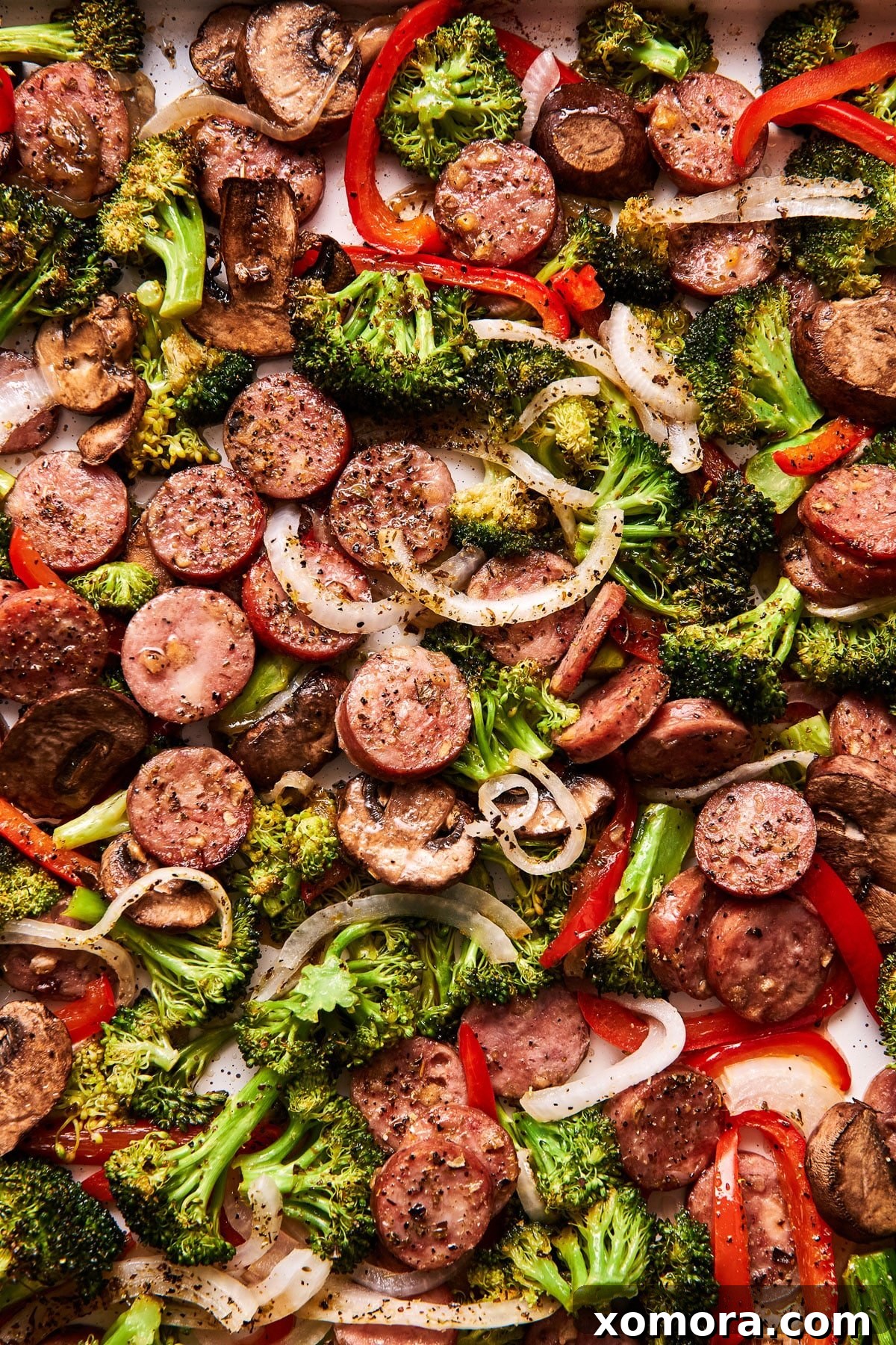 Sausage & Veggie Power Bowls with Zesty Mustard 5 A bowl filled with roasted sausage and vegetables, topped with a creamy mustard sauce.