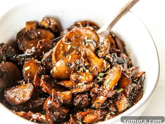 A bowl of sautéed garlic mushrooms, glistening with butter and herbs, ready to be served, with a hint of a rustic background.