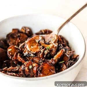 A top-down view of sautéed garlic mushrooms in a serving bowl, garnished with fresh parsley.