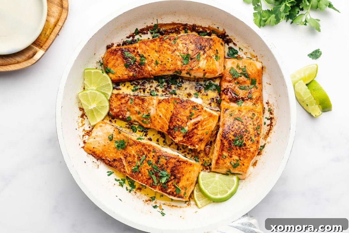Smoky Zesty Salmon Skillet 5 Four pan-seared salmon fillets in a skillet with lime wedges.