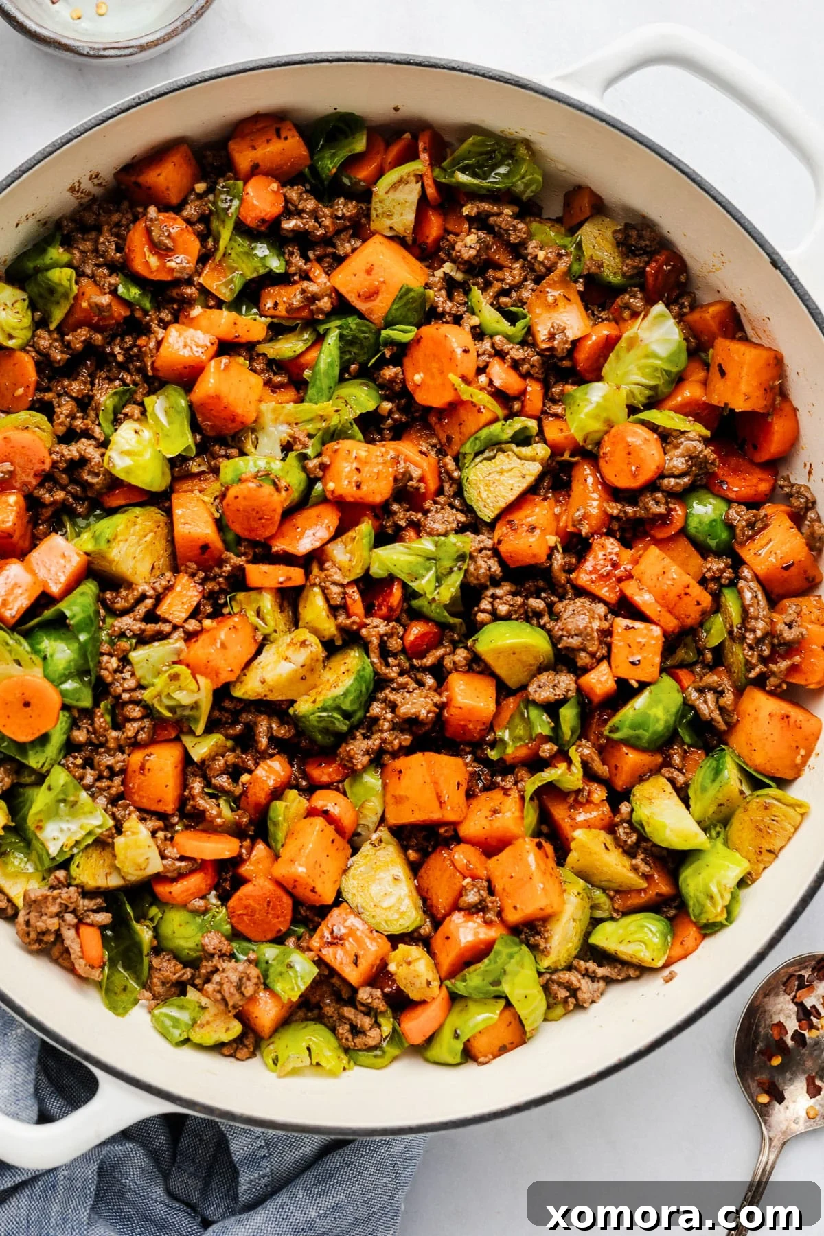 Savory Beef and Sweet Potato Hash 2 A top-down shot of a large skillet filled with cooked ground beef, diced sweet potatoes, carrots, and Brussels sprouts, ready to serve.