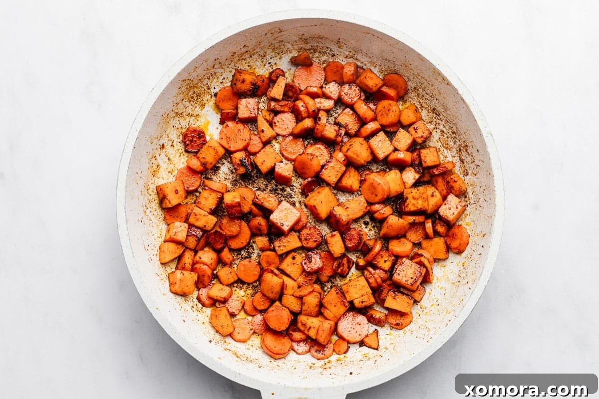 Savory Beef and Sweet Potato Hash 4 Ingredients for the ground beef and sweet potato skillet laid out on a wooden cutting board, including diced sweet potatoes, carrots, Brussels sprouts, ground beef, and various spices.