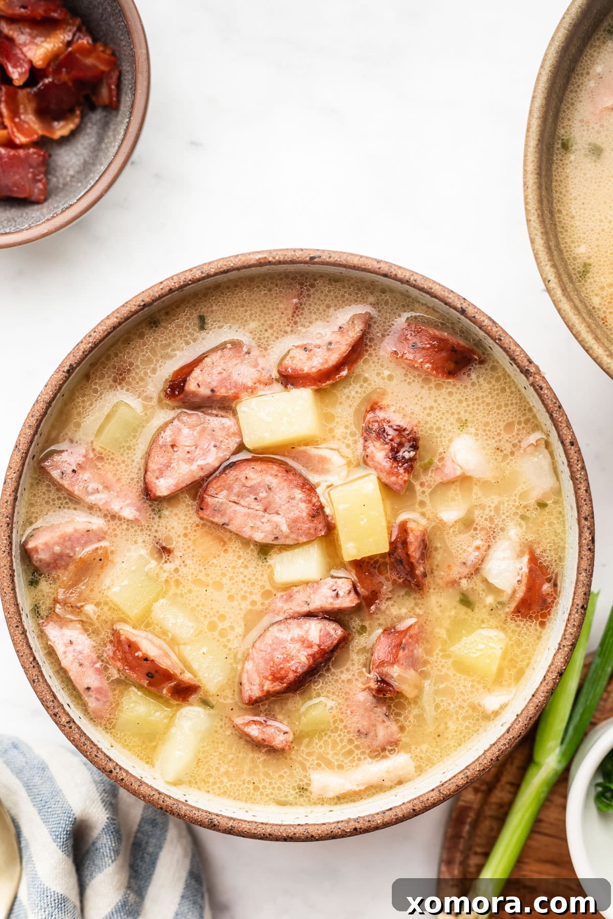 Comforting Sausage and Spud Chowder 6 Six bowls of Creamy Sausage and Potato Soup on a wooden board, ready to serve.