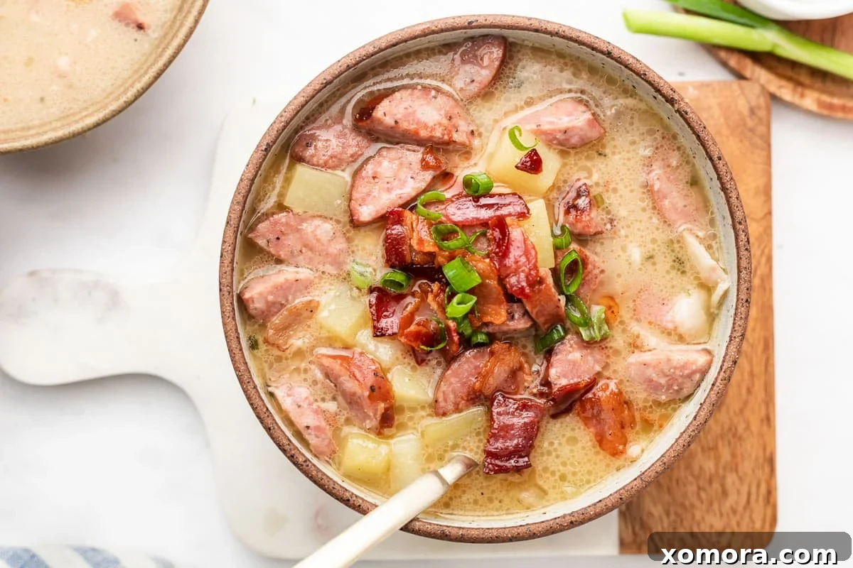 Comforting Sausage and Spud Chowder 7 A single bowl of Creamy Sausage and Potato Soup with a spoon, ready to eat.
