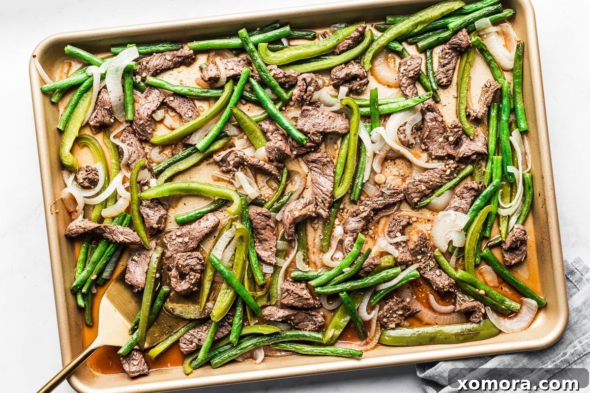 Effortless Sheet Pan Beef Tips and Roasted Veggies 5 A delicious serving of broiled beef tips with a colorful array of vegetables on a white plate.