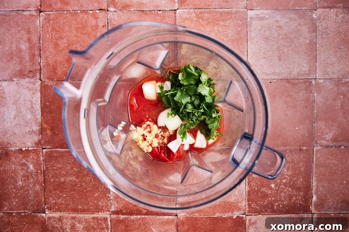 Quick 5 Minute Blender Salsa Restaurant Quality 4 All the fresh ingredients for 5-minute blender salsa, including canned tomatoes, onion, cilantro, jalapeno, and lime, laid out on a wooden cutting board, ready for preparation.