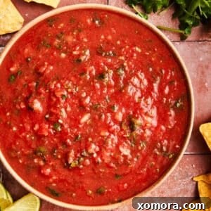 Quick 5 Minute Blender Salsa Restaurant Quality 7 Close-up of freshly blended restaurant-style salsa in a small round bowl, garnished with a sprig of cilantro.