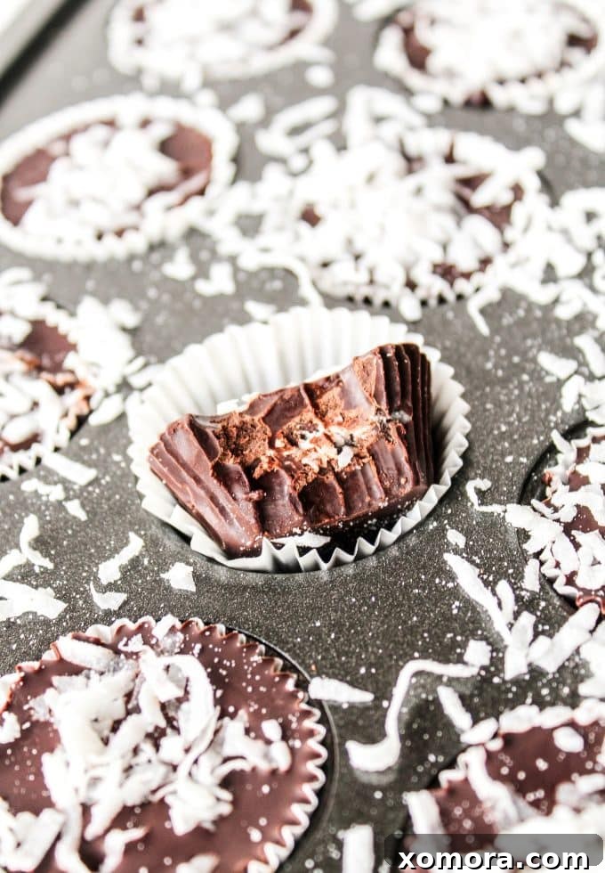 Dark Chocolate Coconut Bliss Bites 3 Key ingredients for making dark chocolate coconut cups: a bowl of dark chocolate chips, a container of coconut oil, and a bag of sweetened coconut flakes