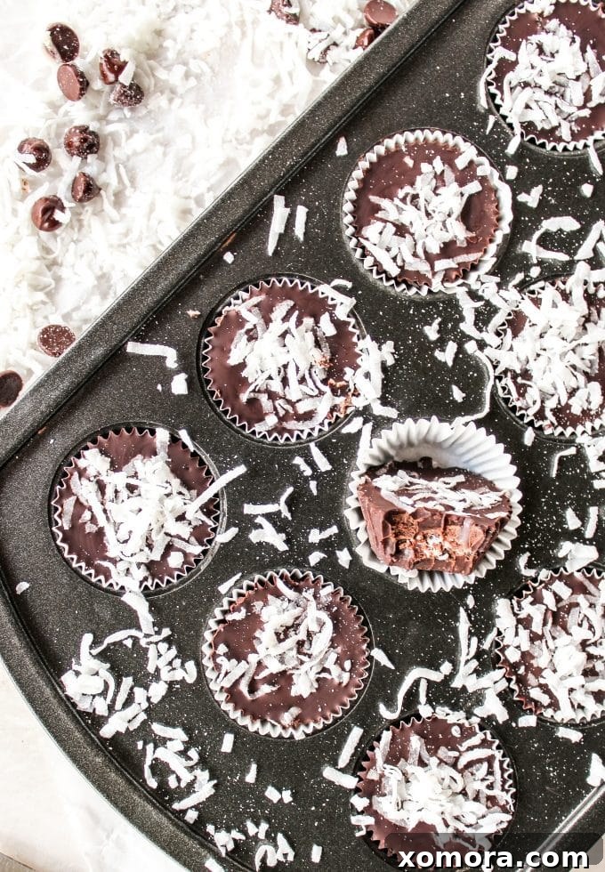Dark Chocolate Coconut Bliss Bites 6 A hand reaching out to grab a dark chocolate coconut cup, showcasing the irresistible nature of the homemade treat