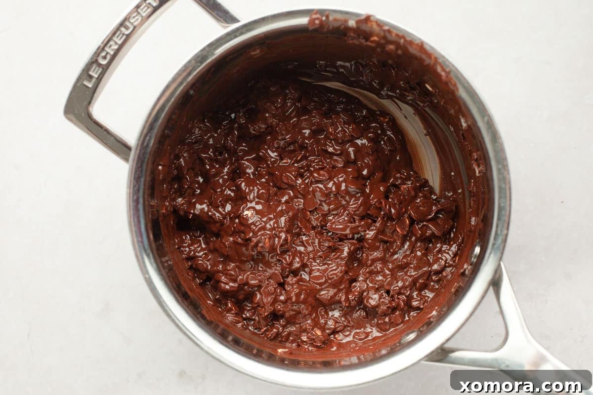Melted chocolate and coconut oil being stirred in a saucepan.