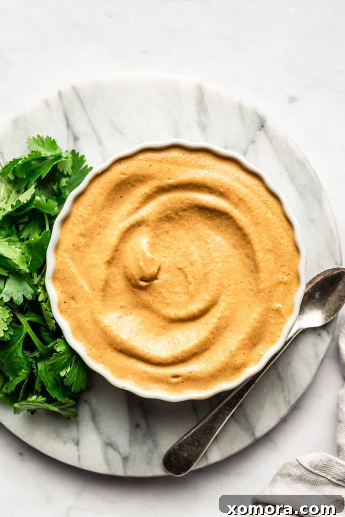 Dairy-free cashew queso drizzled over a plate of roasted vegetables.