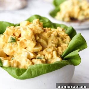 A close-up overhead shot of a finished bowl of creamy Easy Classic Egg Salad, garnished with fresh herbs, ready for serving.
