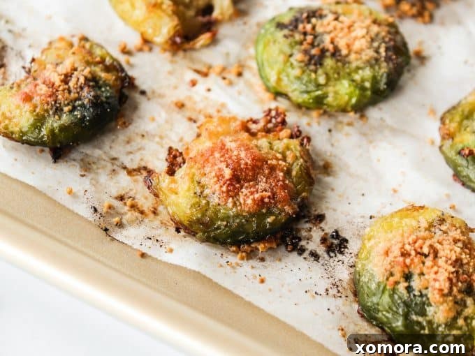Crispy Parmesan Smashed Brussels Sprouts 3 Close-up of smashed brussels sprouts on parchment paper, ready for seasoning.