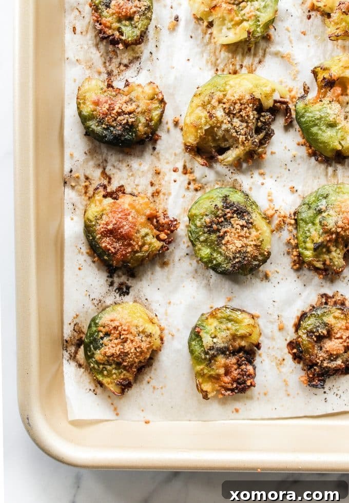 Crispy Parmesan Smashed Brussels Sprouts 4 Platter of perfectly roasted Smashed Parmesan Brussels Sprouts, garnished with fresh herbs.