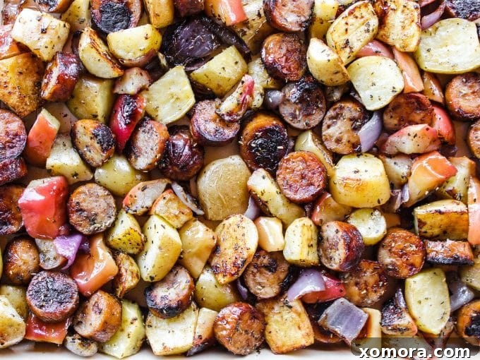 Individual pieces of roasted sausage, apple, and potato, showing the rich caramelization and tender texture, served fresh from the oven.