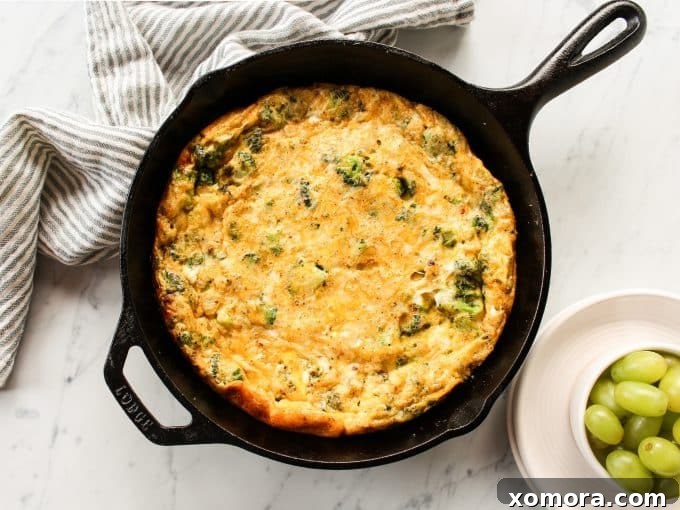 Fluffy Broccoli Cheddar Frittata 3 Close-up shot of the Broccoli Cheddar Frittata cooking in a cast iron skillet, showcasing the melted cheese and vibrant broccoli.