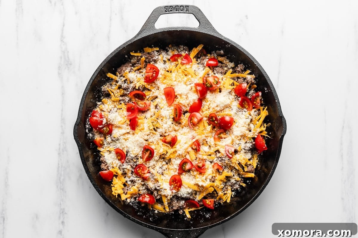 Cheeseburger Egg Bake 4 Ingredients for Cheeseburger Frittata including eggs, various cheeses, ground meat, and fresh tomatoes, laid out on a table