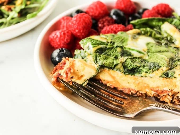 Individual slices of Bacon Spinach Frittata arranged on a white plate with a garnish of fresh herbs, ready for serving.