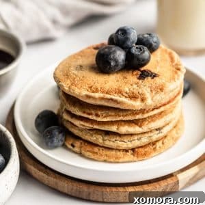 Blueberry Oat Power Pancakes 5 A beautifully presented stack of Healthy Blueberry Oat Pancakes on a plate.