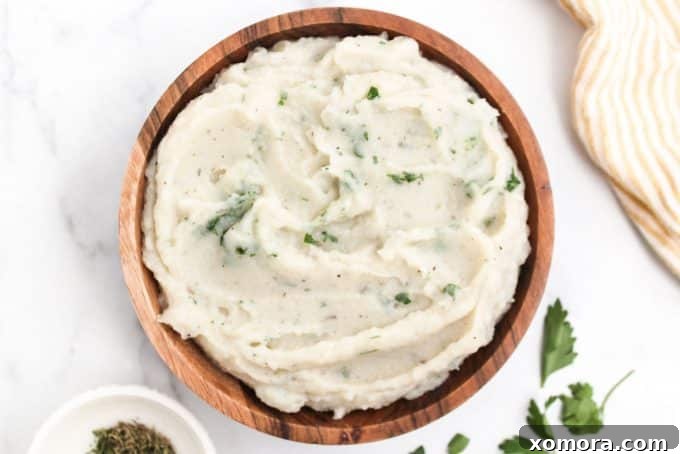 Velvety Cauliflower Mash 5 A bowl of creamy cauliflower mashed potatoes topped with fresh herbs and a drizzle of melted butter.