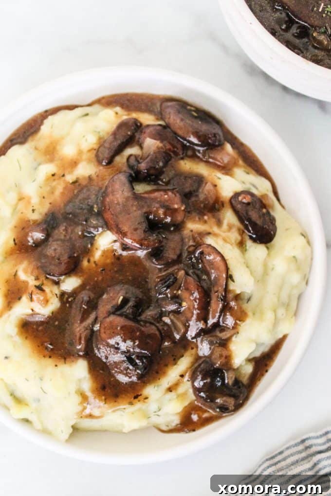 Effortless Umami Mushroom Gravy 3 A close-up of the finished mushroom gravy in a white serving bowl, showcasing its rich texture and chunks of mushrooms.