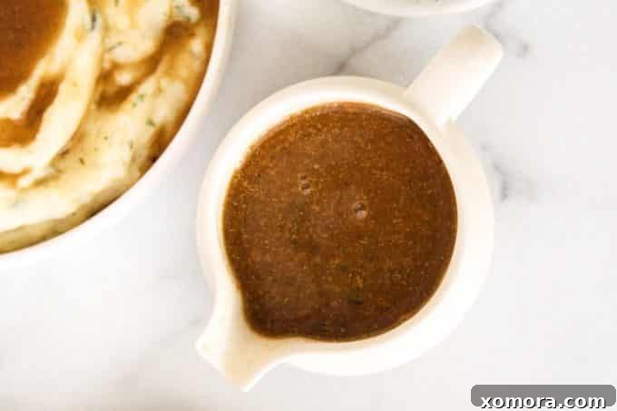 A bowl of vegan gravy drizzled over fluffy mashed potatoes, ready to be served.