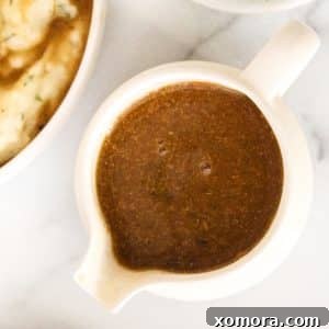 A top-down view of a serving of vegan gravy in a small white bowl, ready to be poured.