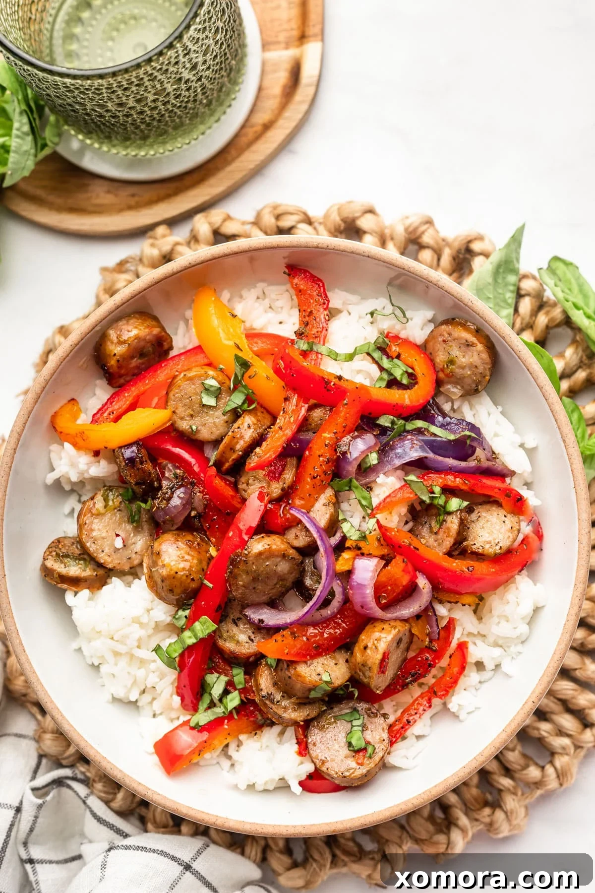 Effortless Roasted Italian Sausage and Peppers 6 A serving of sheet pan sausage and peppers over rice, garnished with fresh basil.