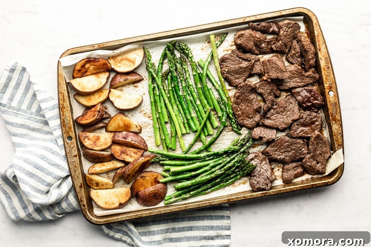 Sheet Pan Steakhouse at Home 4 A sheet pan with roasted steak, asparagus, and potato wedges, ready to be served.