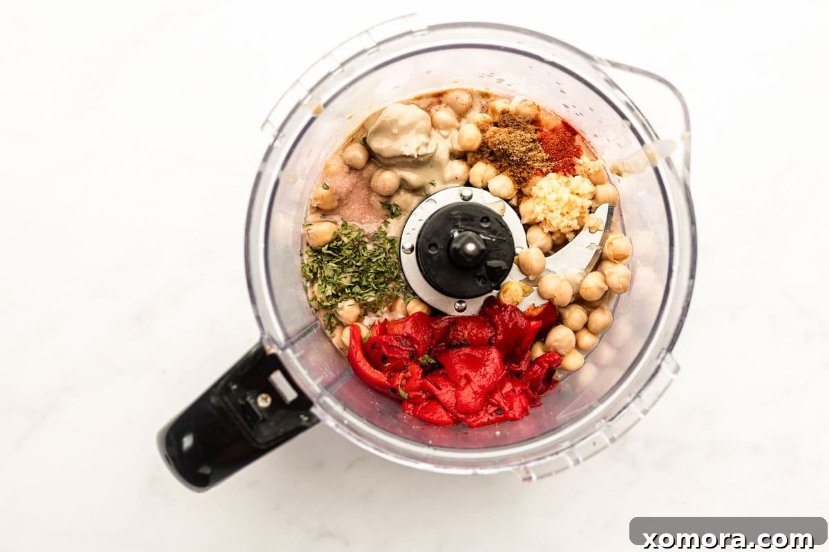 Fire-Kissed Pepper Hummus 3 A jar of tahini with a spoon, alongside a bowl of chickpeas, lemon, and olive oil, showing key hummus ingredients.