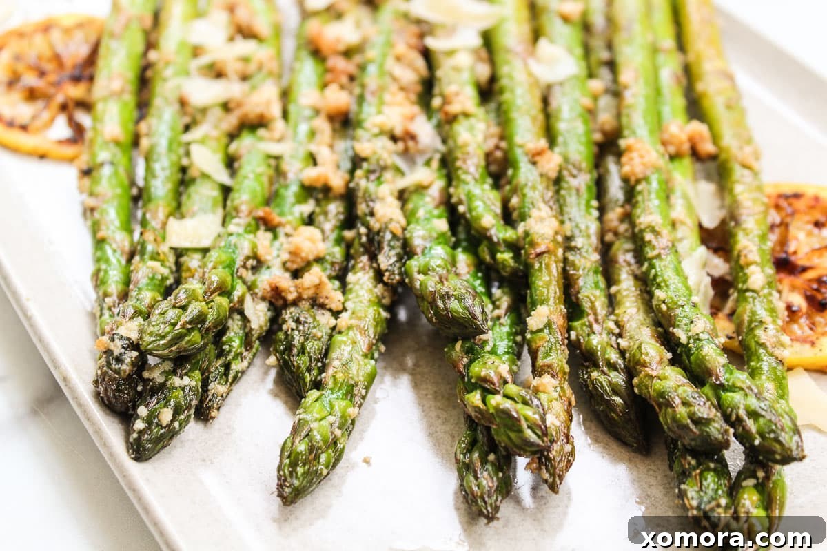 Golden Parmesan Asparagus 3 A bundle of fresh, vibrant green asparagus on a rustic wooden cutting board, ready for preparation.