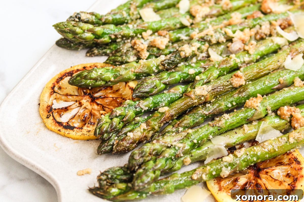 Golden Parmesan Asparagus 4 A vibrant serving of sautéed lemon parmesan asparagus on a pristine white plate, garnished with fresh lemon slices.