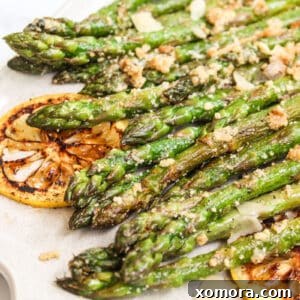 Sautéed Parmesan Asparagus with lemon slices, close-up.