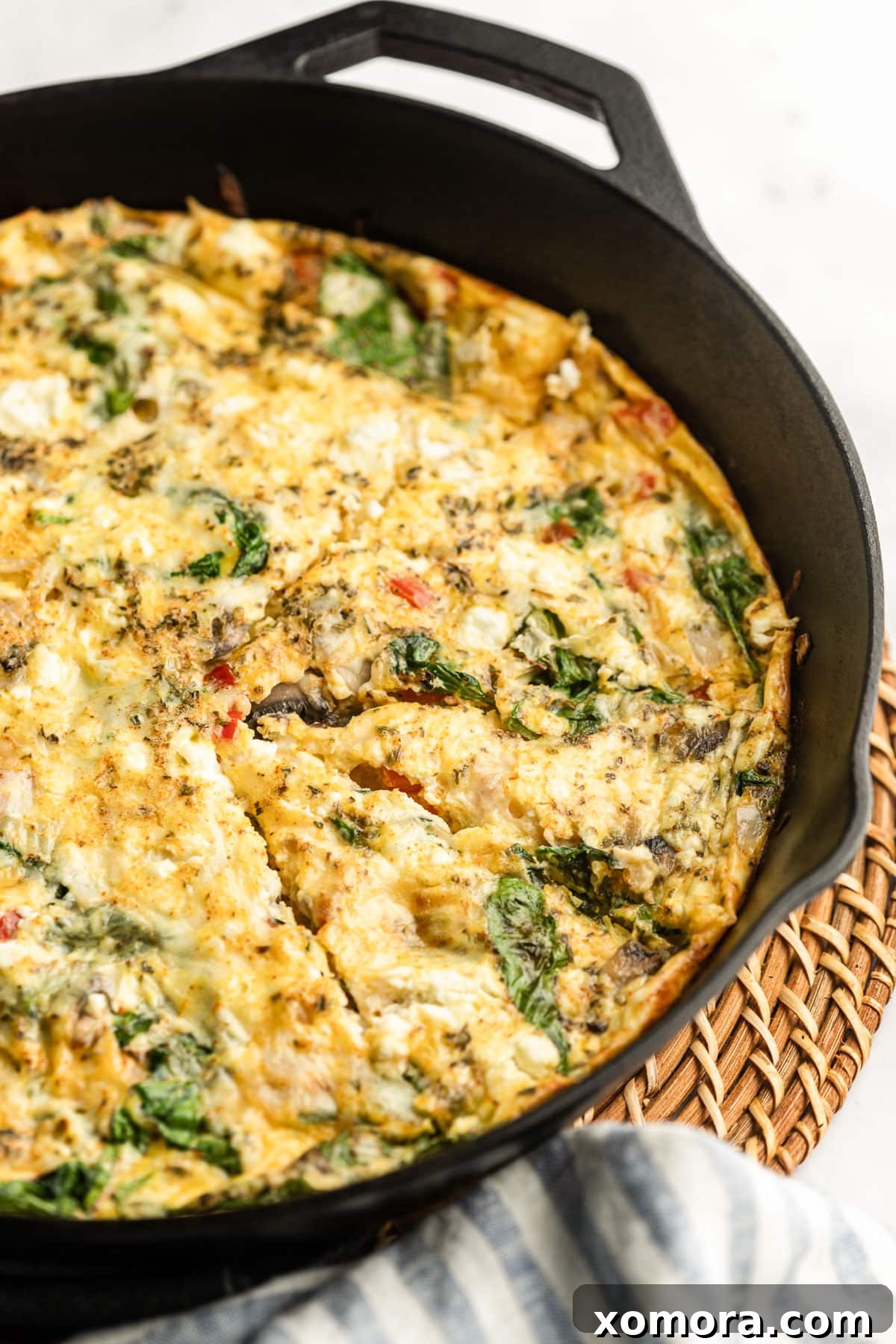 Close-up of golden brown Vegetable Frittata baking in a cast iron skillet.