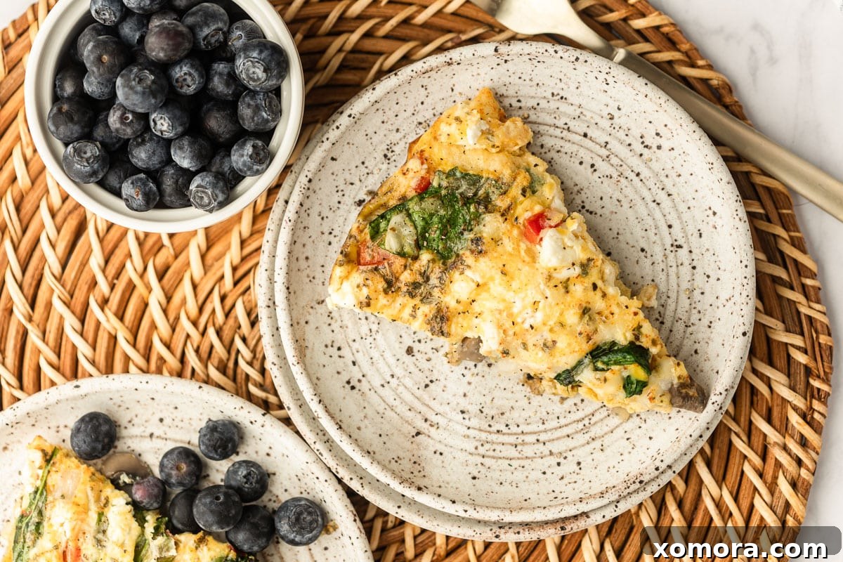 A slice of Vegetable Frittata on a plate with fresh fruit.