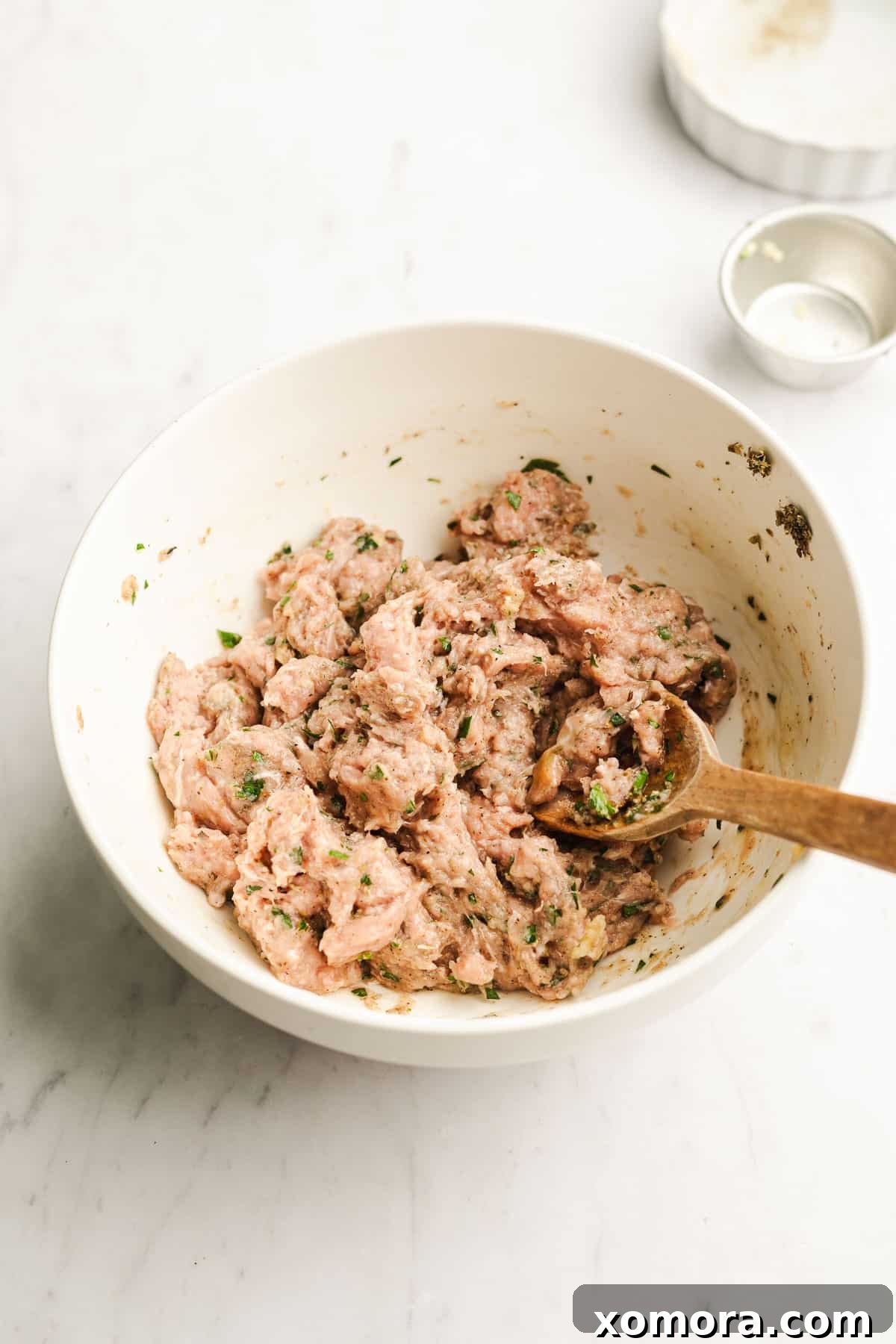Raw turkey meatball mixture being formed into balls in a large mixing bowl.