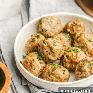 A bowl of air fryer turkey meatballs garnished with fresh herbs, ready to be served.