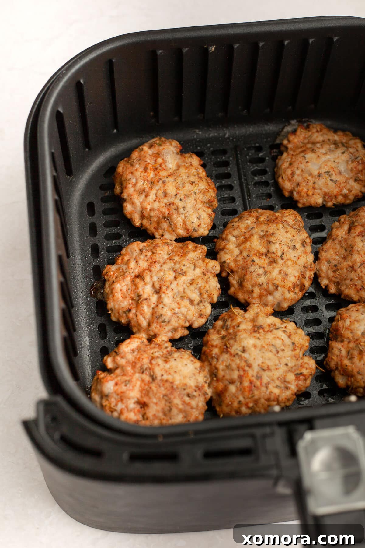 Crispy Air-Fried Turkey Breakfast Links 4 Cooked air fryer turkey breakfast sausage patties piled on a plate, garnished with fresh herbs, ready to serve.