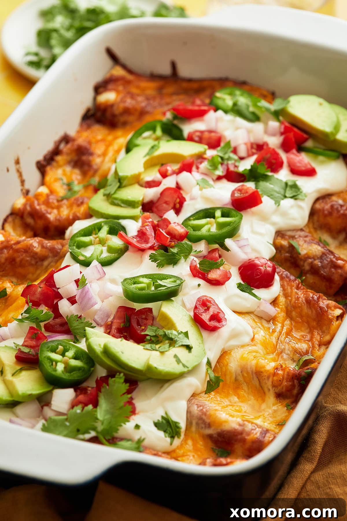 Effortless Cheesy Chicken Enchiladas 2 Delicious chicken enchiladas in a baking dish, freshly baked and topped with melted cheese.