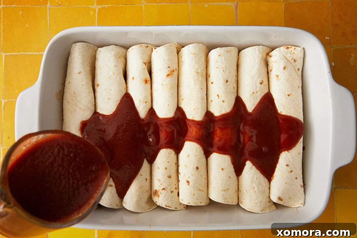Effortless Cheesy Chicken Enchiladas 4 Enchiladas rolled and arranged in a baking dish, ready for sauce and cheese.